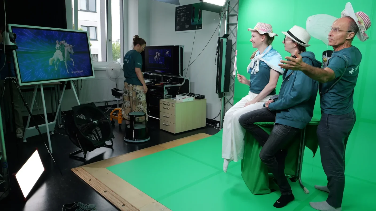 Team in campus42-Shirts posiert mit Hüten und Flügeln vor dem Greenscreen