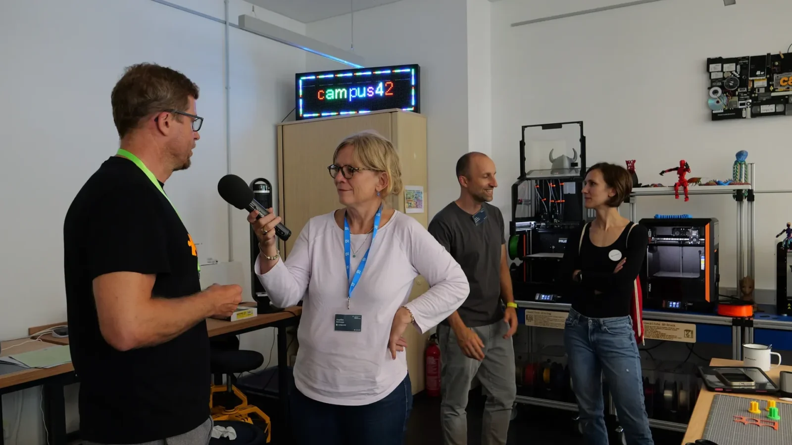 Radio-Interview mit Mikrofon im Makerspace, im Hintergrund LED-Laufschrift „campus42"