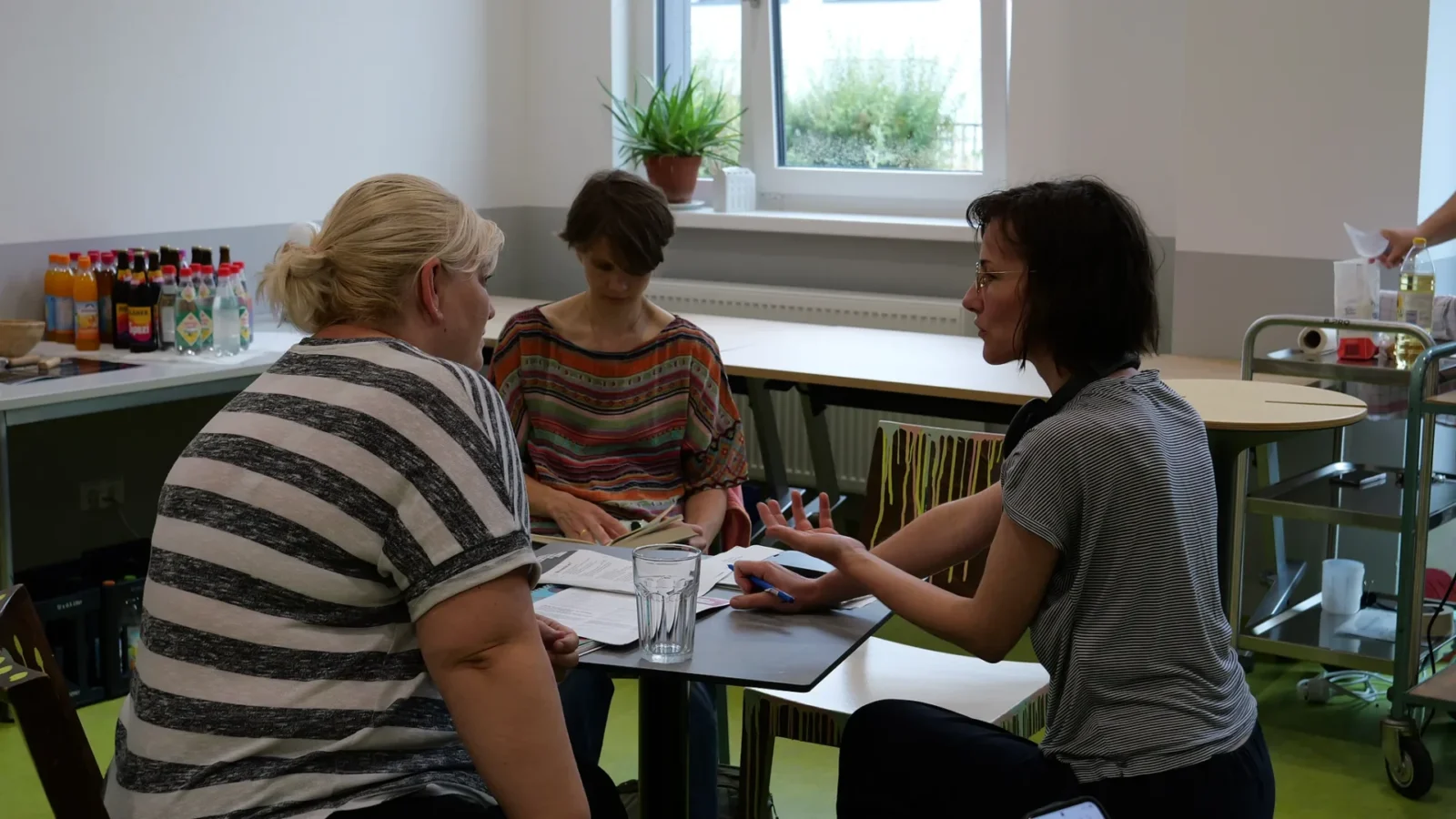 Drei Frauen im Gespräch an einem kleinen Tisch mit Unterlagen