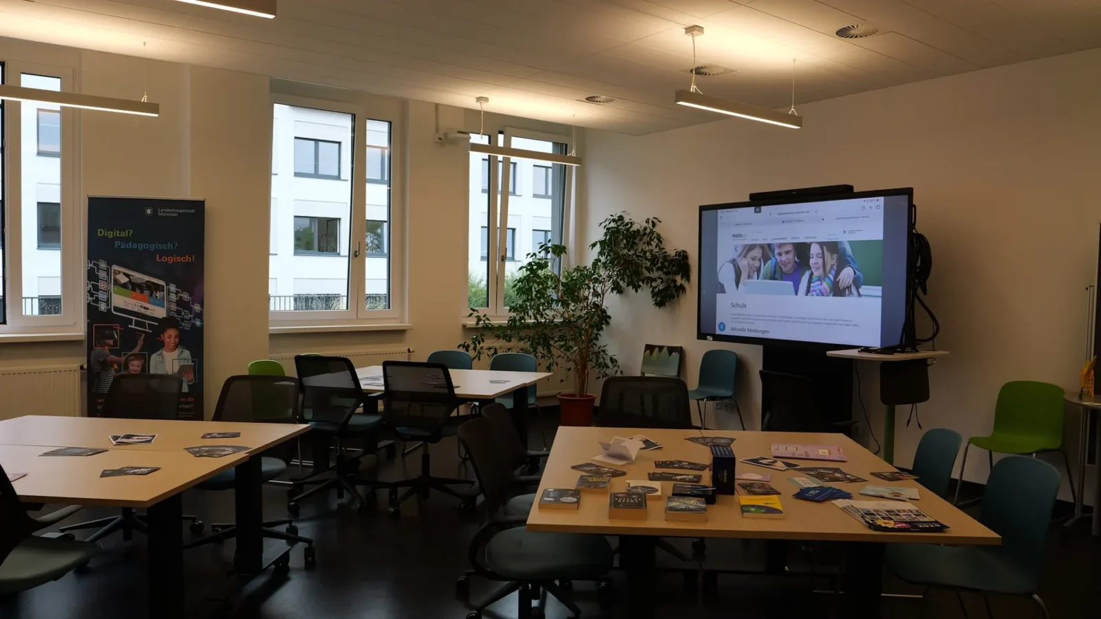 Leerer Seminarraum mit Großdisplay, das die Website Medienbildung München zeigt