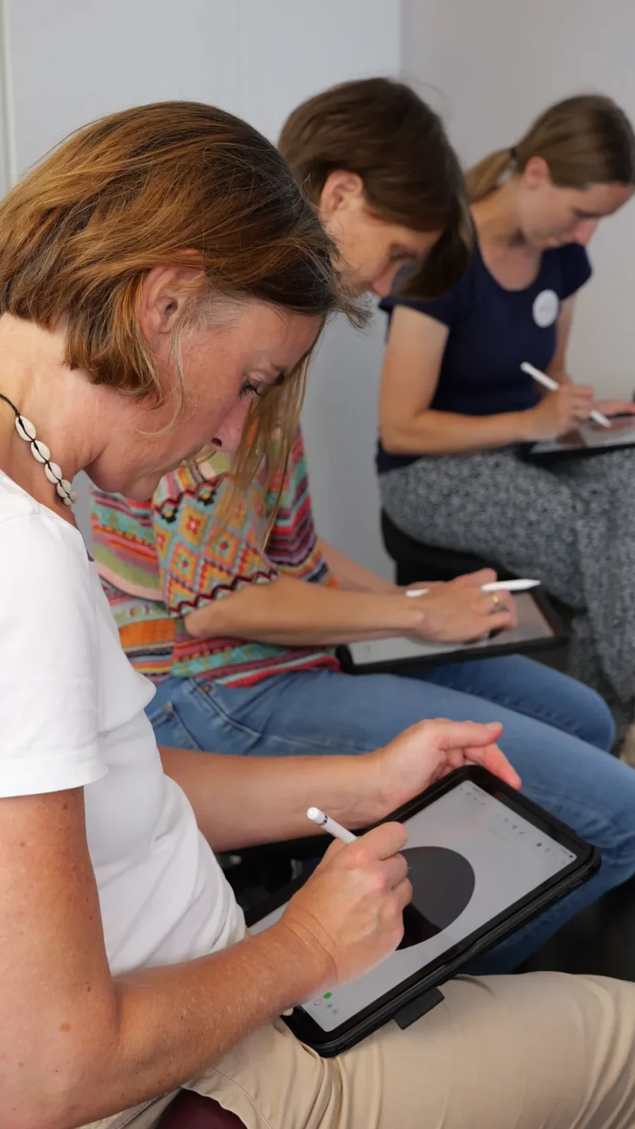 Drei Teilnehmerinnen zeichnen konzentriert mit Stift auf iPads