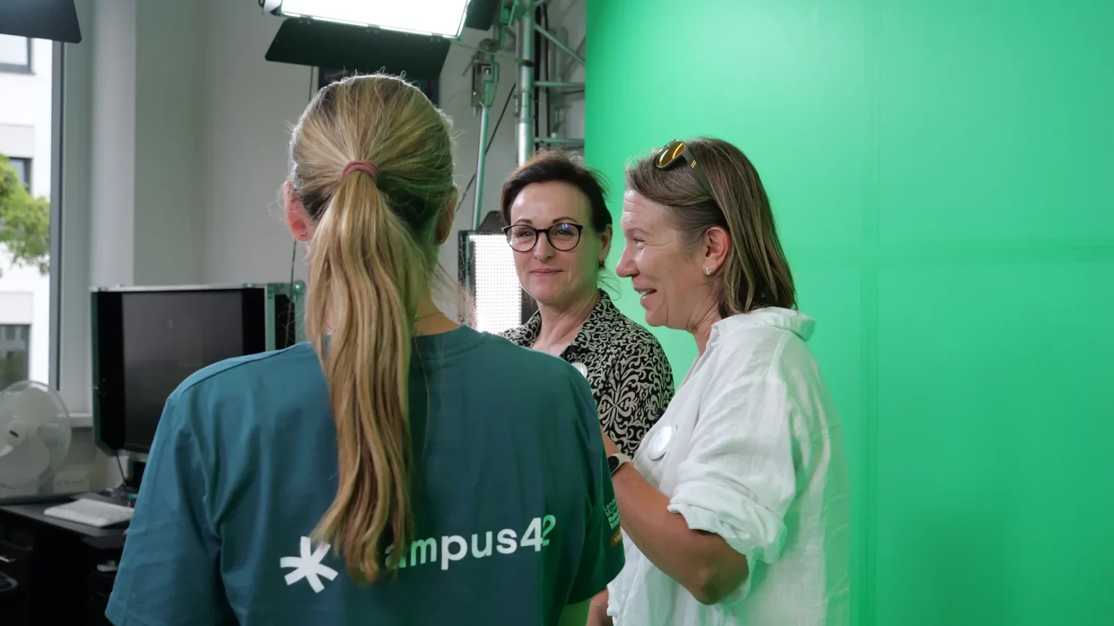 Gespräch vor der Greenscreen-Wand im Filmstudio, Studioleuchten im Hintergrund