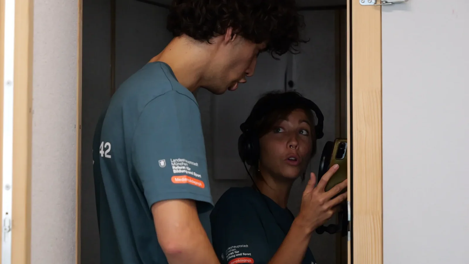 In der Schallschutzkabine liest eine Frau mit Kopfhörern vom Smartphone ab