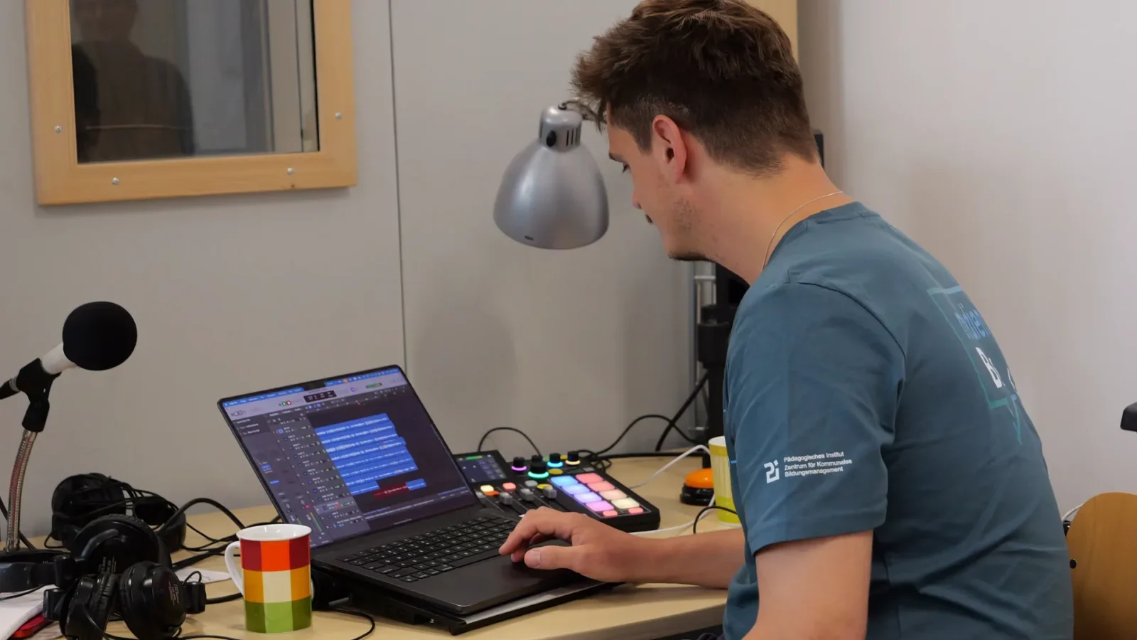 Mitarbeiter schneidet Audiospuren in einer Musiksoftware am Laptop, daneben ein Rodecaster-Pult