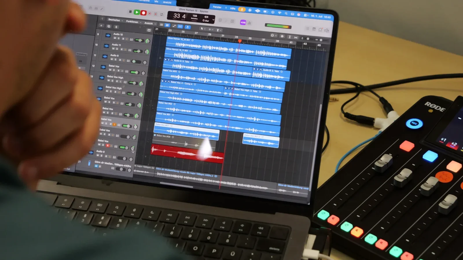 Blick über die Schulter auf einen Laptop mit Musiksoftware, daneben ein RØDE-Mischpult