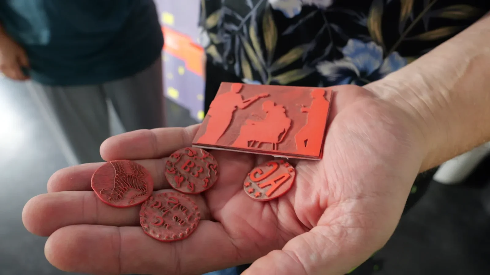 Handfläche mit lasergeschnittenen roten Chips und einer Reliefkarte aus dem Makerspace