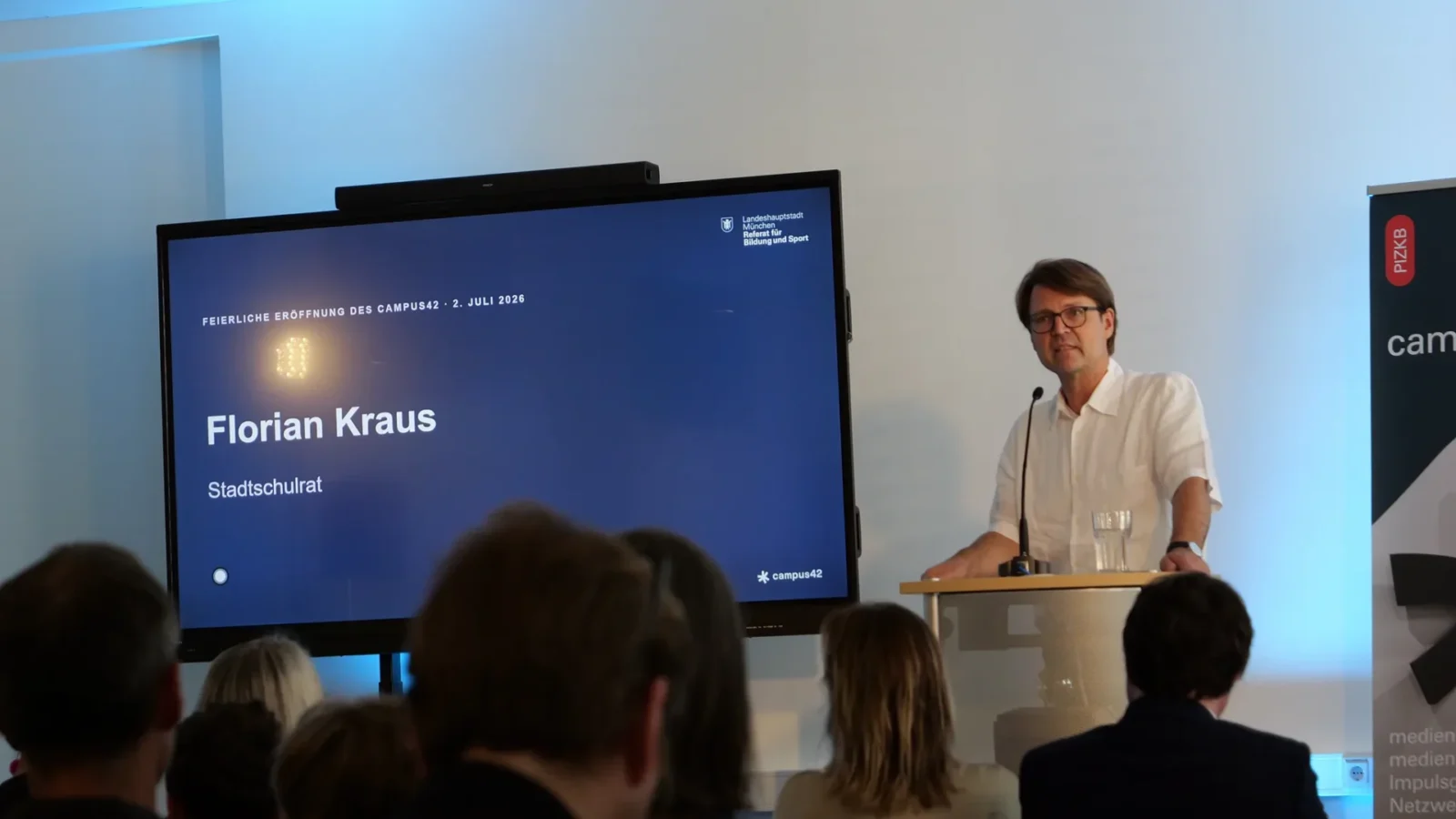 Stadtschulrat spricht am Rednerpult, Bildschirm: „Feierliche Eröffnung des campus42 – 2. Juli 2026"