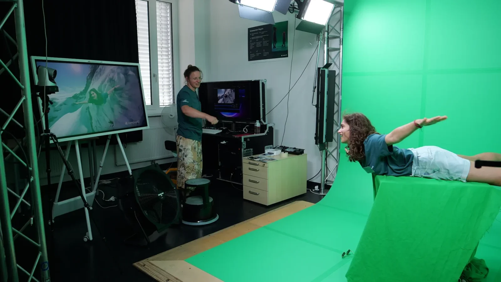 Greenscreen in Aktion: Auf dem Monitor schwebt die posierende Person über einer Berglandschaft
