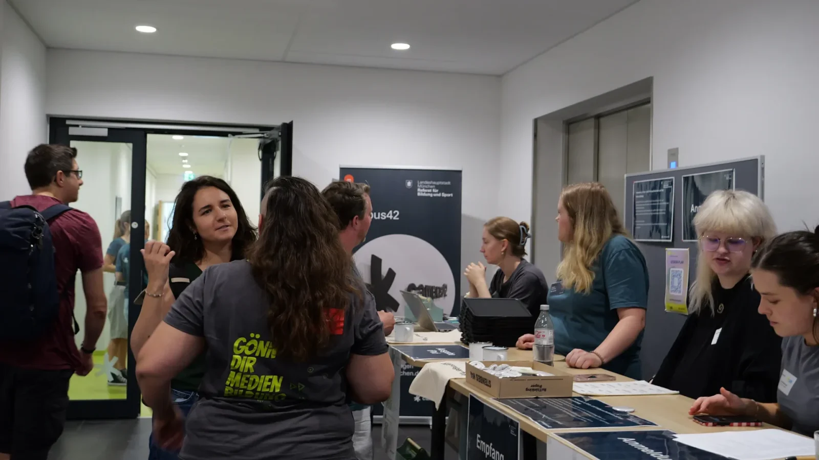 Anmeldung im Foyer: Teilnehmende am Check-in-Tisch mit iPads vor dem campus42-Rollup